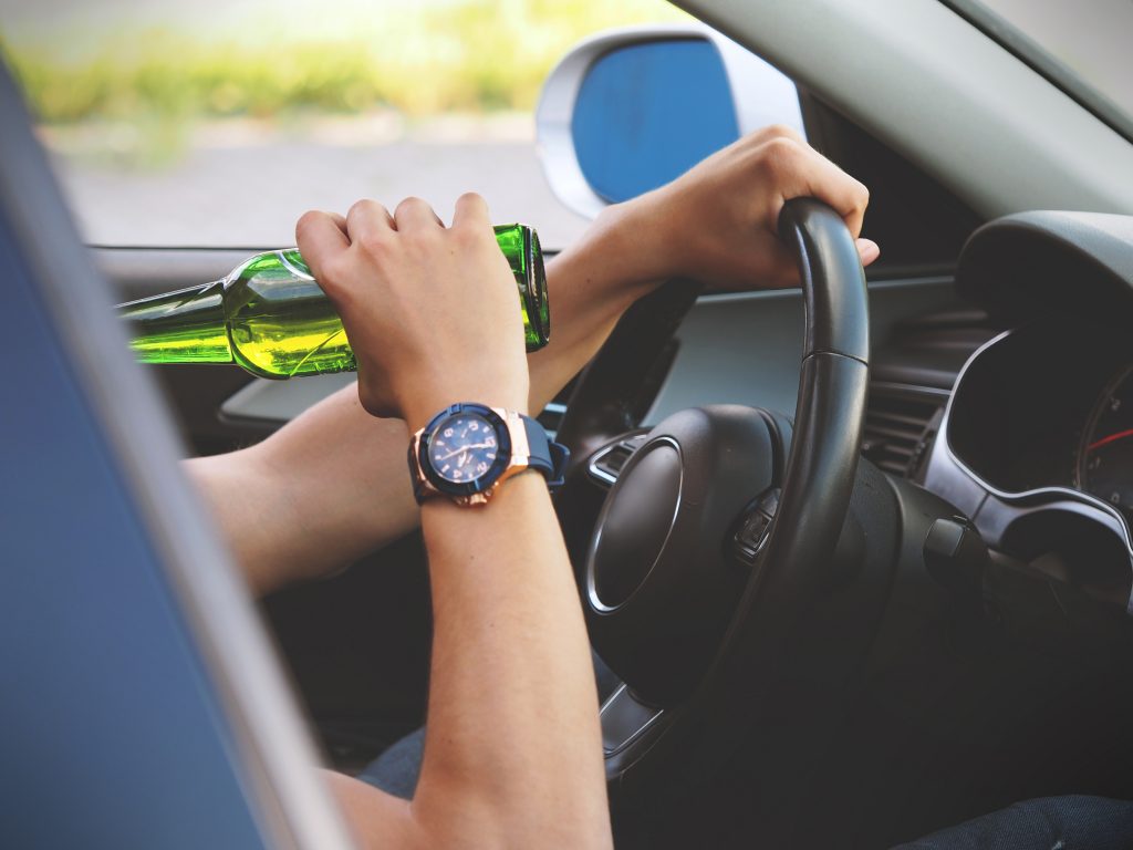 Picture of a person drinking while driving.
